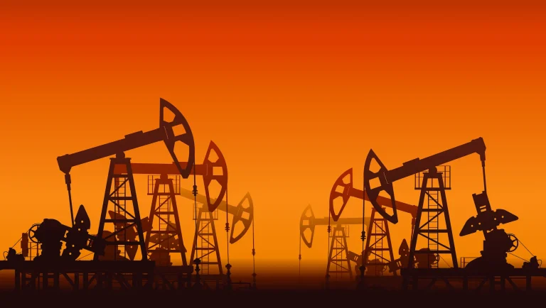 Oil pumpjacks silhouetted against an orange sunset