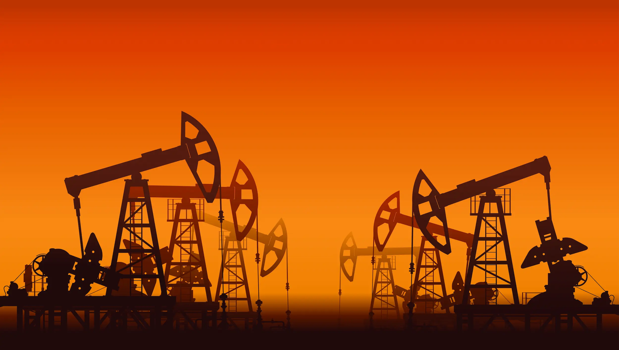 Oil pumpjacks silhouetted against an orange sunset