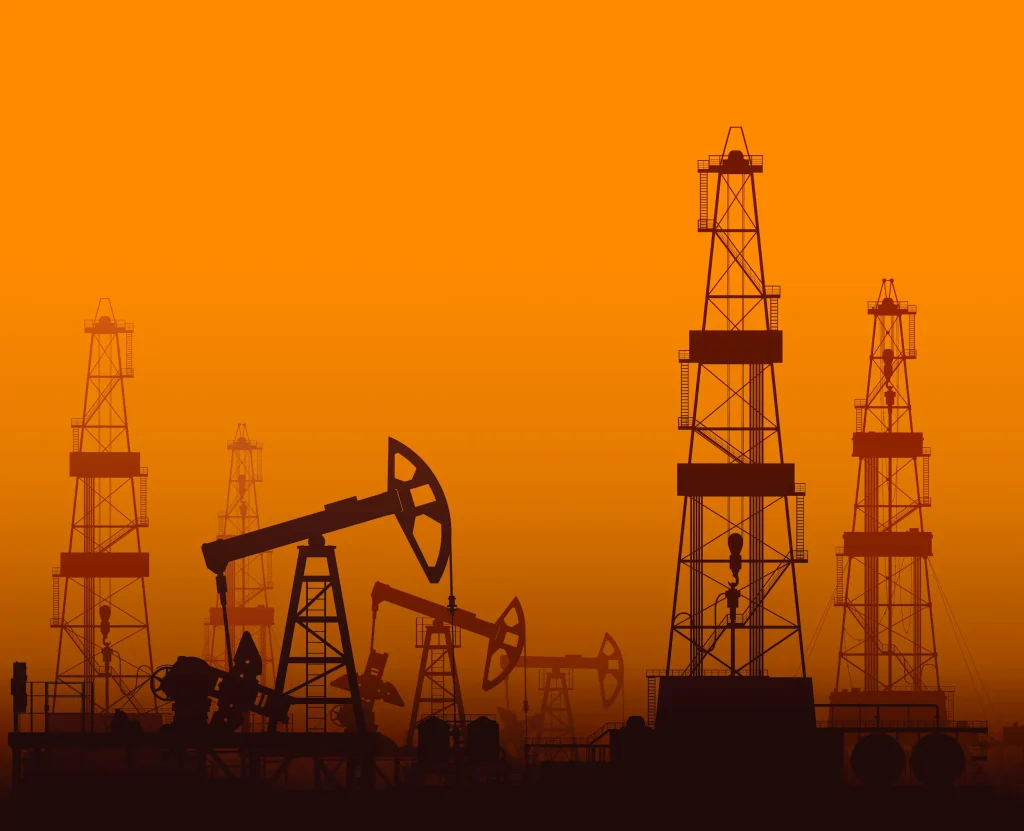 Oil rigs and pumpjacks silhouetted at sunset