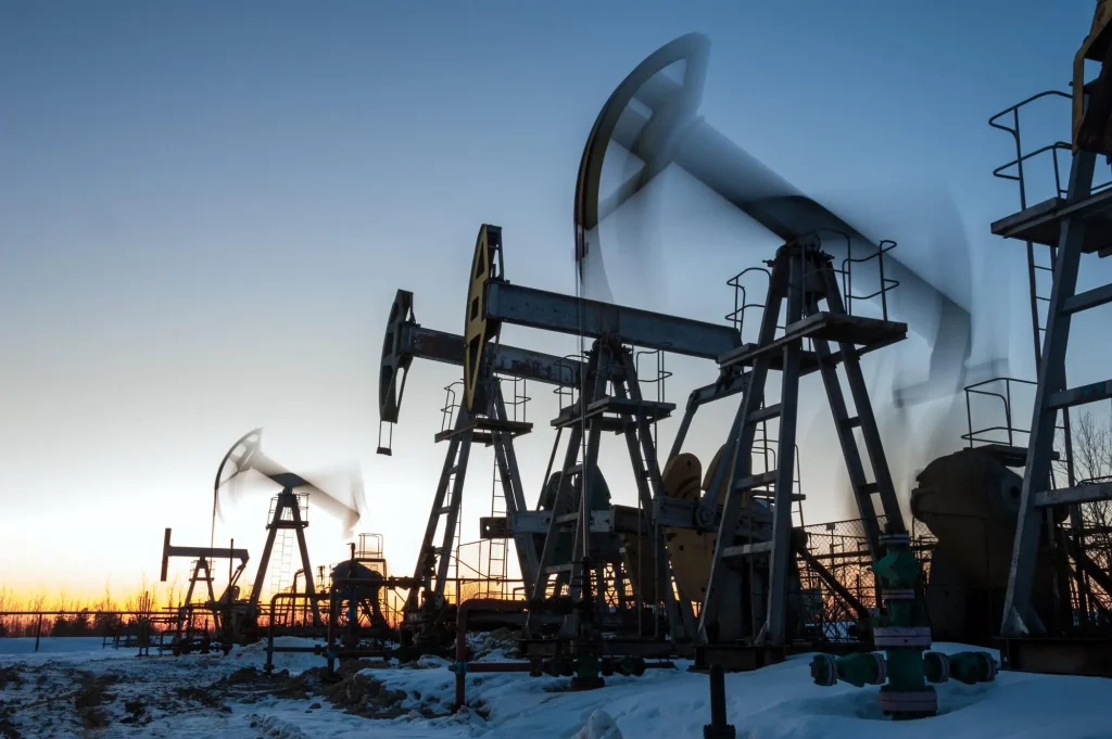 Pumpjacks on a snowy oil field at dusk